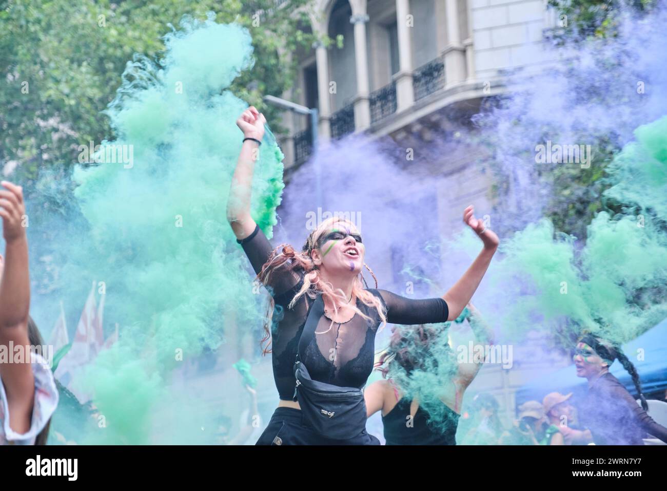 Buenos Aires, Argentinien; 8. März 2024: Euphorische junge Frau springt und schreien in einer Wolke aus grünem und violettem Rauch während der 8M International Wom Stockfoto