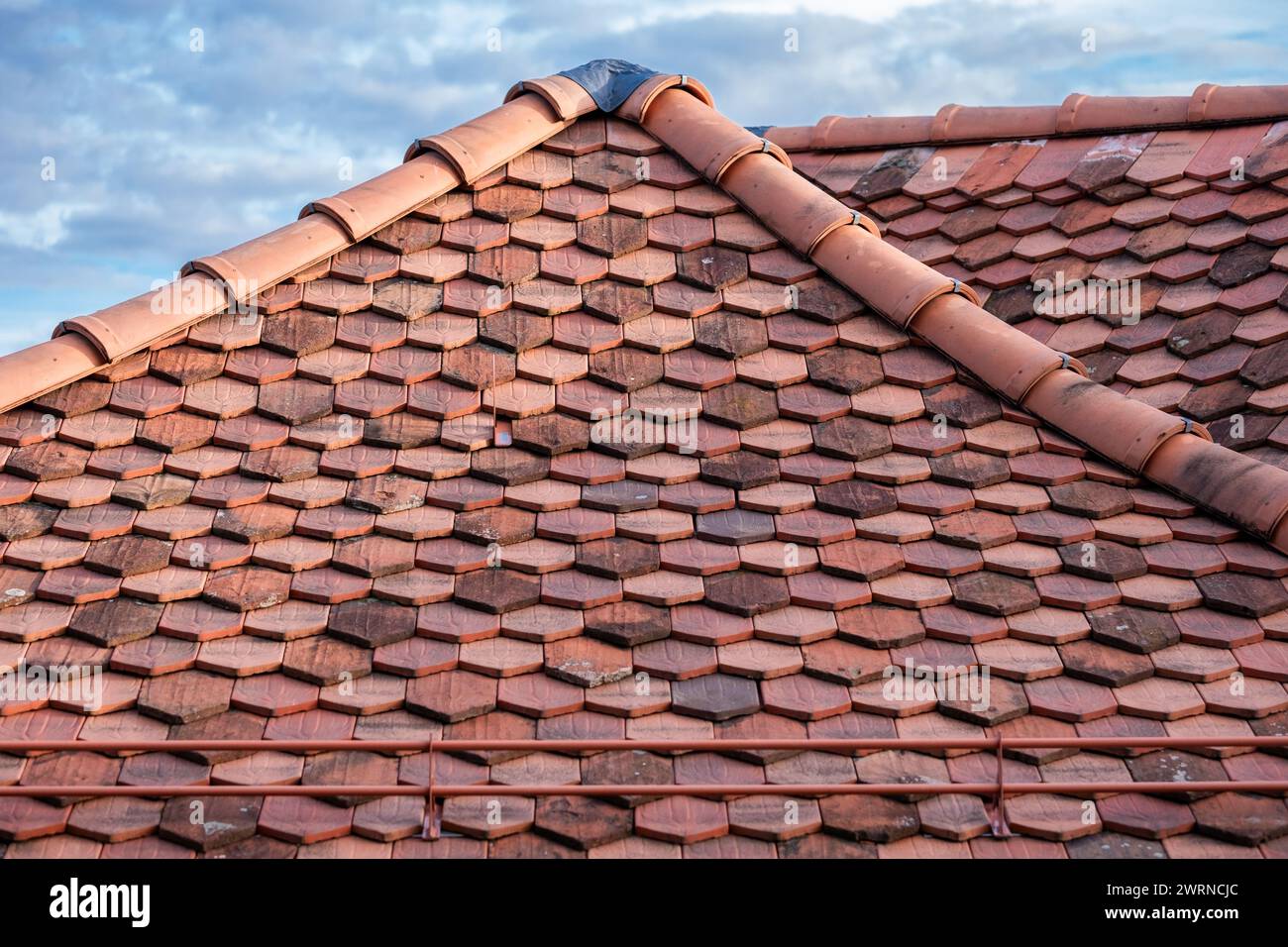 Das robuste, rot gekachelte Dach, das in sanftes Licht getaucht ist, verkörpert Langlebigkeit und langfristigen Schutz für Häuser sowie Wetterbeständigkeit. Hohe Qualität Stockfoto