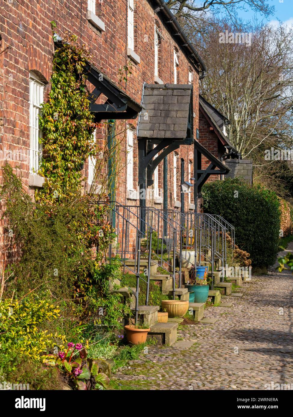 Reihe traditioneller Hütten entlang einer Kopfsteinpflasterstraße im Dorf Styal. Wilmslow, Cheshire, Großbritannien Stockfoto