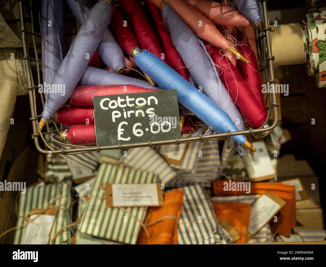 Pirnen aus bunten Baumwollfäden in einem Drahtkorb. Stockfoto
