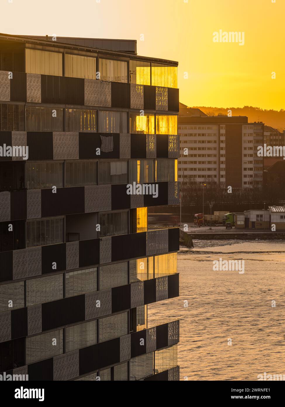 Die Sonne untergeht über dem Wasser und wirft ein warmes goldenes Licht auf die Gebäude im Hintergrund. Die Szene erfasst den Übergang von Tag zu Nacht, Stockfoto