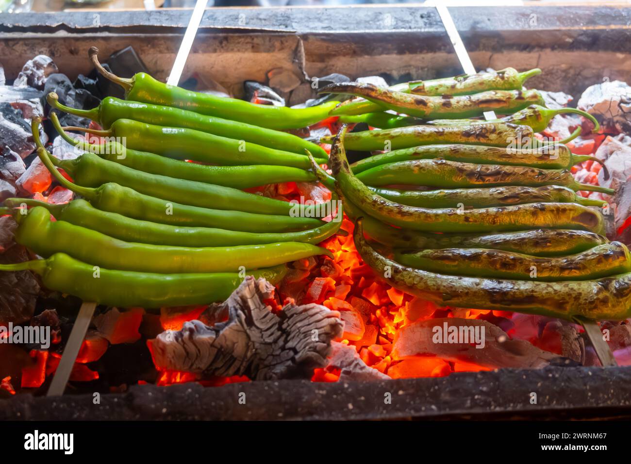 Barbecue mit grüner türkischer Paprika auf geflammtem Holzkohlegrill im türkischen Restaurant Stockfoto