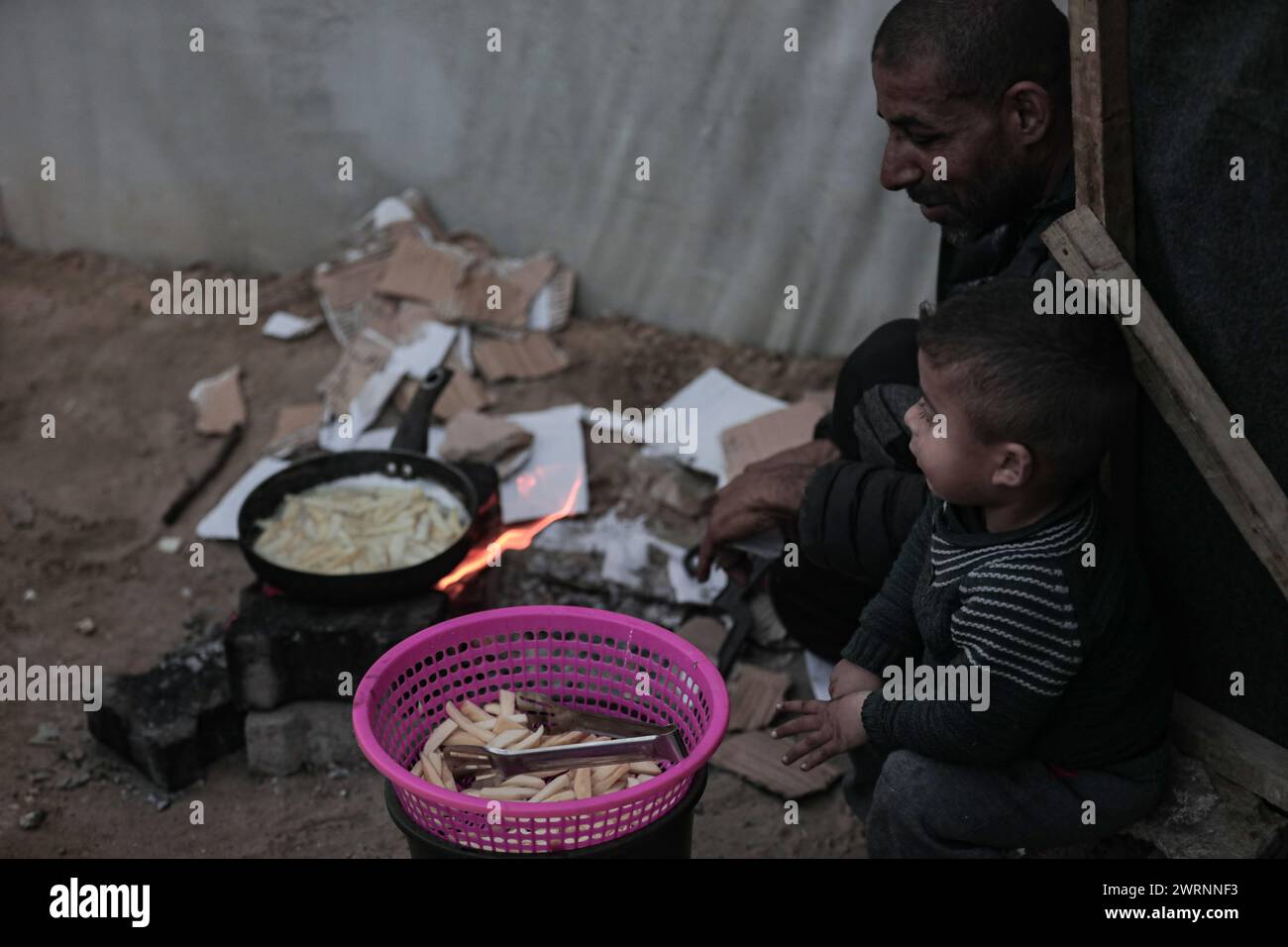 März 2024, Deir Al Balah, Gazastreifen, Palästina: Gaza, Palästina. 13. März 2024. Vertriebene Palästinenser kochen sehr einfache Lebensmittel außerhalb ihrer Zelte rund um das Shuhada al-Aqsa Krankenhaus in Deir al-Balah, im mittleren Bereich des Gazastreifens. Die düstere Lage im Gazastreifen setzt sich unvermindert fort, während israelische Streiks und kaum humanitäre Hilfe in die vom Krieg verwüstete palästinensische Enklave gelangen. Nach Angaben des Gazastreifens gesundheitsministerium sind 27 Menschen, die meisten davon Kinder, an Unterernährung und Dehydratation gestorben, wobei die Behandlung von Hungersnot ständig zunimmt (Credit Image: © Adel Al Hwajre/IMAGESL Stockfoto