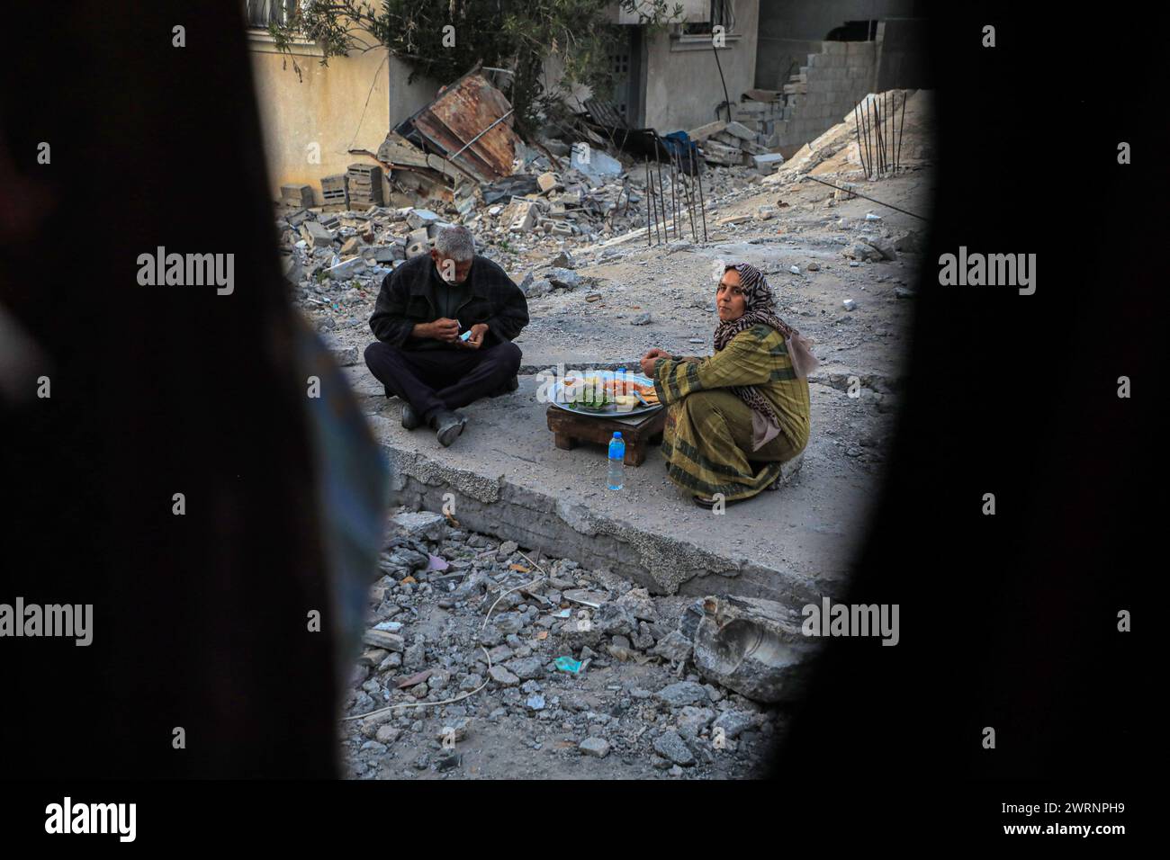 Deir El Balah. März 2024. Die Palästinenser brechen ihr Fasten während des Ramadan am 13. März 2024 auf den Trümmern ihres Hauses in Deir el-Balah im Zentrum des Gazastreifens. Die Zahl der palästinensischen Todesopfer aufgrund der laufenden israelischen Angriffe auf den Gazastreifen ist auf 31.272 gestiegen, berichtete das in Gaza ansässige Gesundheitsministerium am Mittwoch. Quelle: Rizek Abdeljawad/Xinhua/Alamy Live News Stockfoto