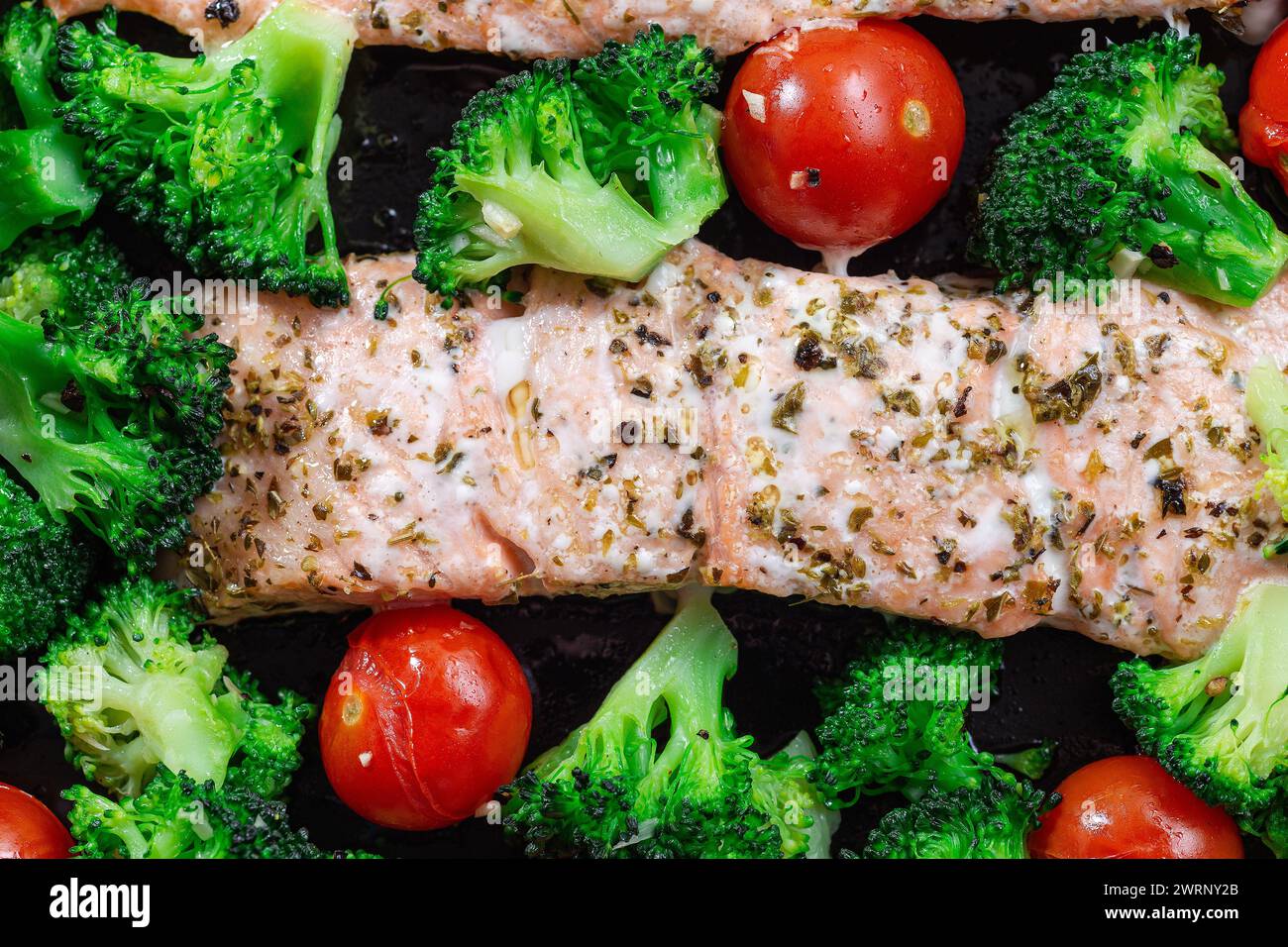 Gebackenes Lachsfilet mit Brokkoli und Tomaten, eine Pfanne, horizontal, Draufsicht, Nahaufnahme Stockfoto