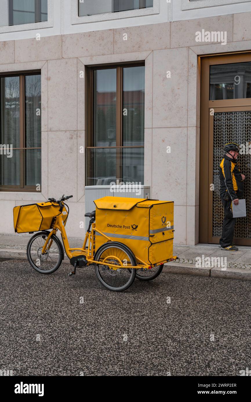 Berlin, Deutschland - 16. Dezember 2021: Leitender Zusteller mit Post auf einem Fahrrad, Mitarbeiter der Deutschen Post. Stockfoto
