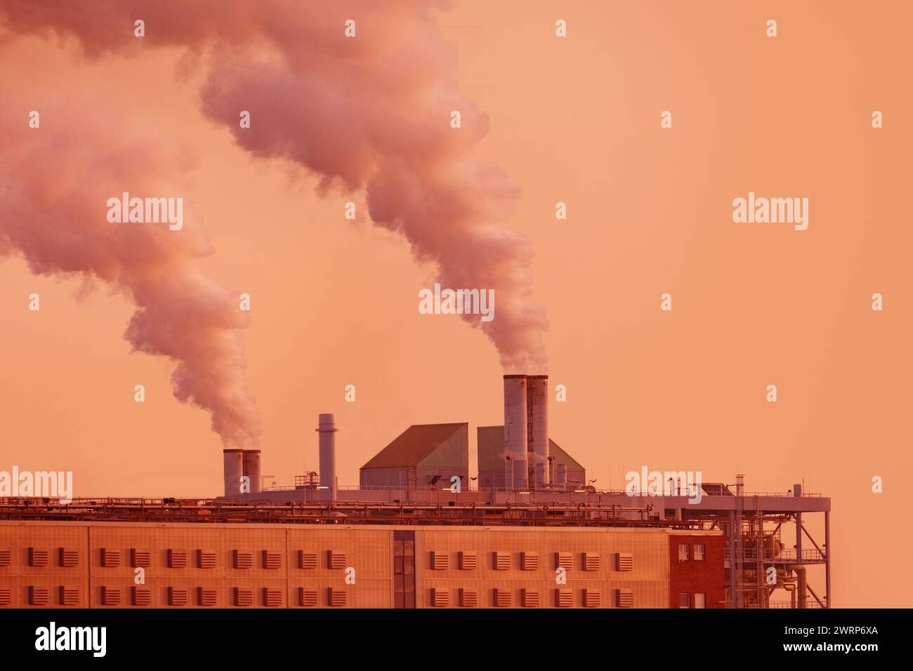 Dramatische Ansichtsfabrik mit Dampf aus dem Kamin, der in den Sonnenuntergang steigt, erfasst Energie und Industrie, Umweltauswirkungen der Industrialisierung Stockfoto