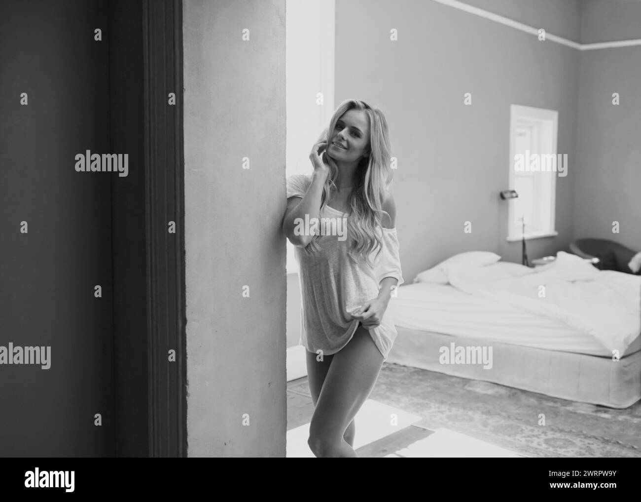 Porträt, Lächeln und Frau für Schlafzimmer im Haus mit lässigen Klamotten in Schwarzweiß-Wohnung allein am Morgen. T-Shirt, Haare und fröhliche Junge Stockfoto