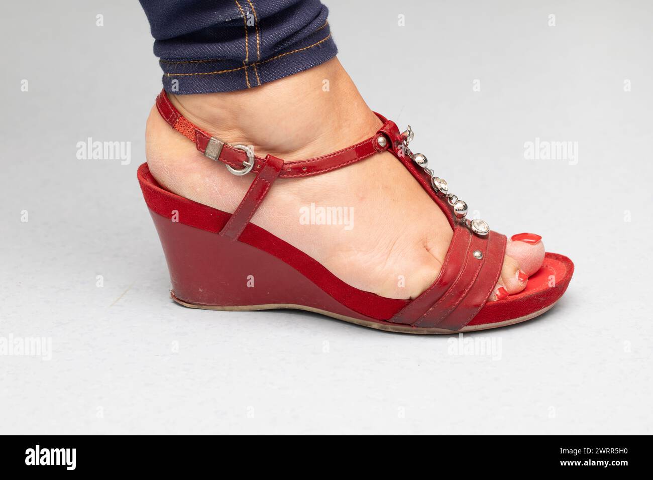 Nahaufnahme eines Frauenfußes in einer stylischen Sandale mit Keilabsatz und dekorativen Details Stockfoto