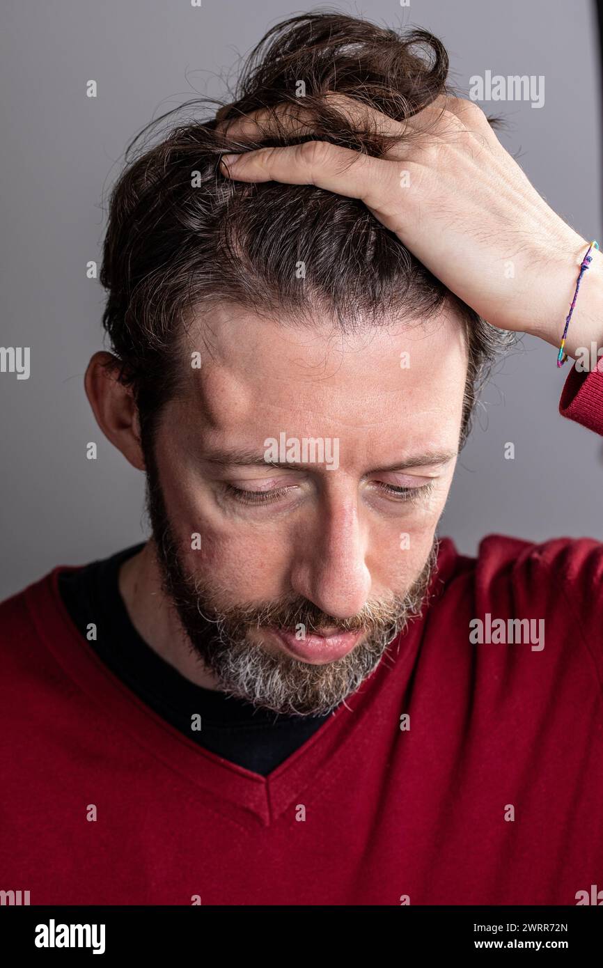 Nahaufnahme eines beunruhigten Mannes, der seinen Kopf untersucht, die Augen geschlossen Stockfoto