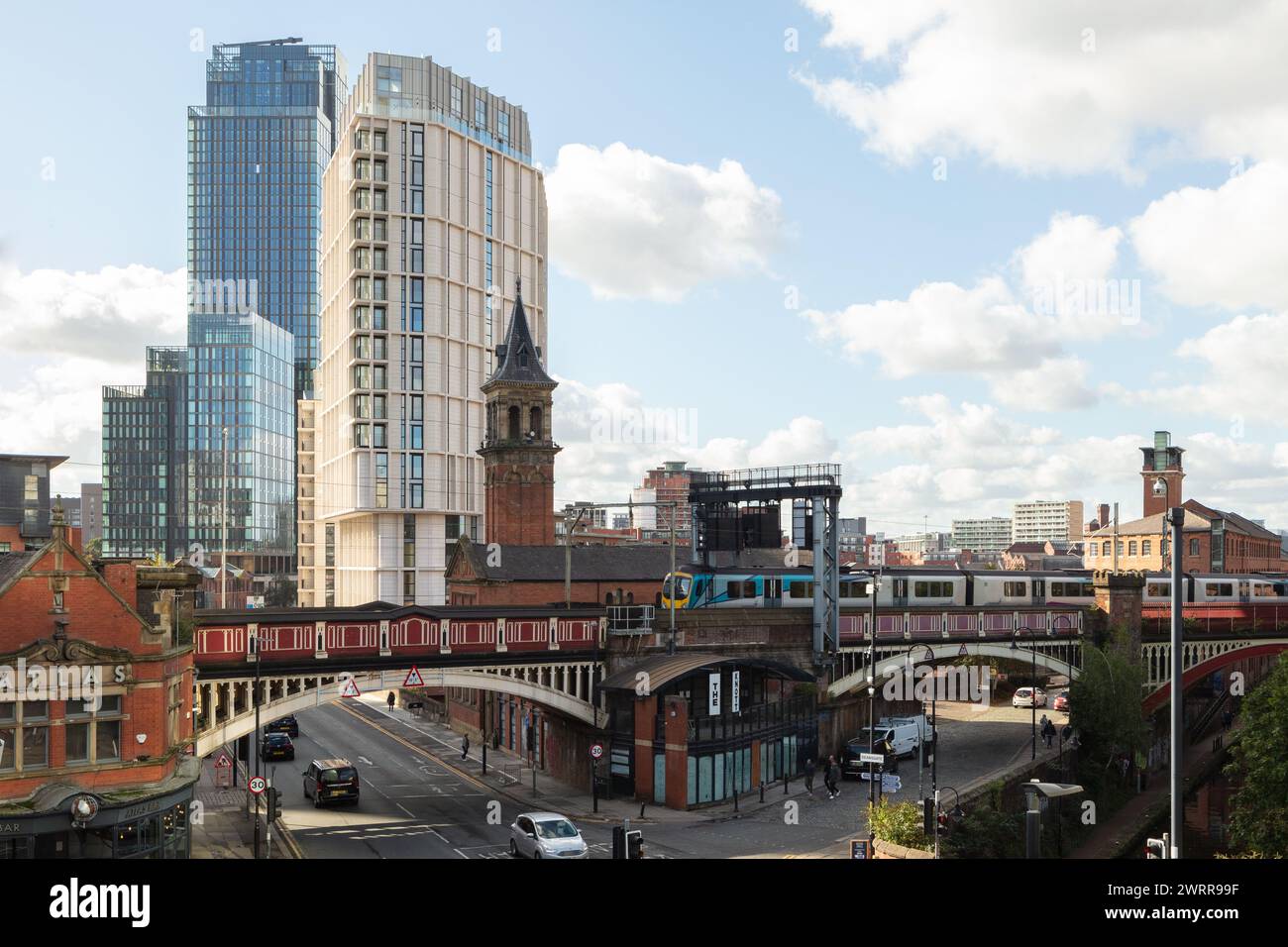 Ein Zug überquert eine Eisenbahnbrücke in die Deansgate Station, Manchester, Großbritannien mit den Apartments Castle Wharf und Deansgate Square im Hintergrund Stockfoto