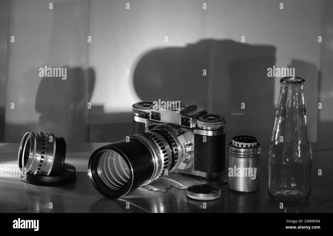 Comeback des Filmfotografiekonzepts mit analoger Kamera, Objektiv, Filmkanister und Kamerafilm im Vintage-Range-Sucher, Schwarzweiß, kostenlosem Kopierraum Stockfoto
