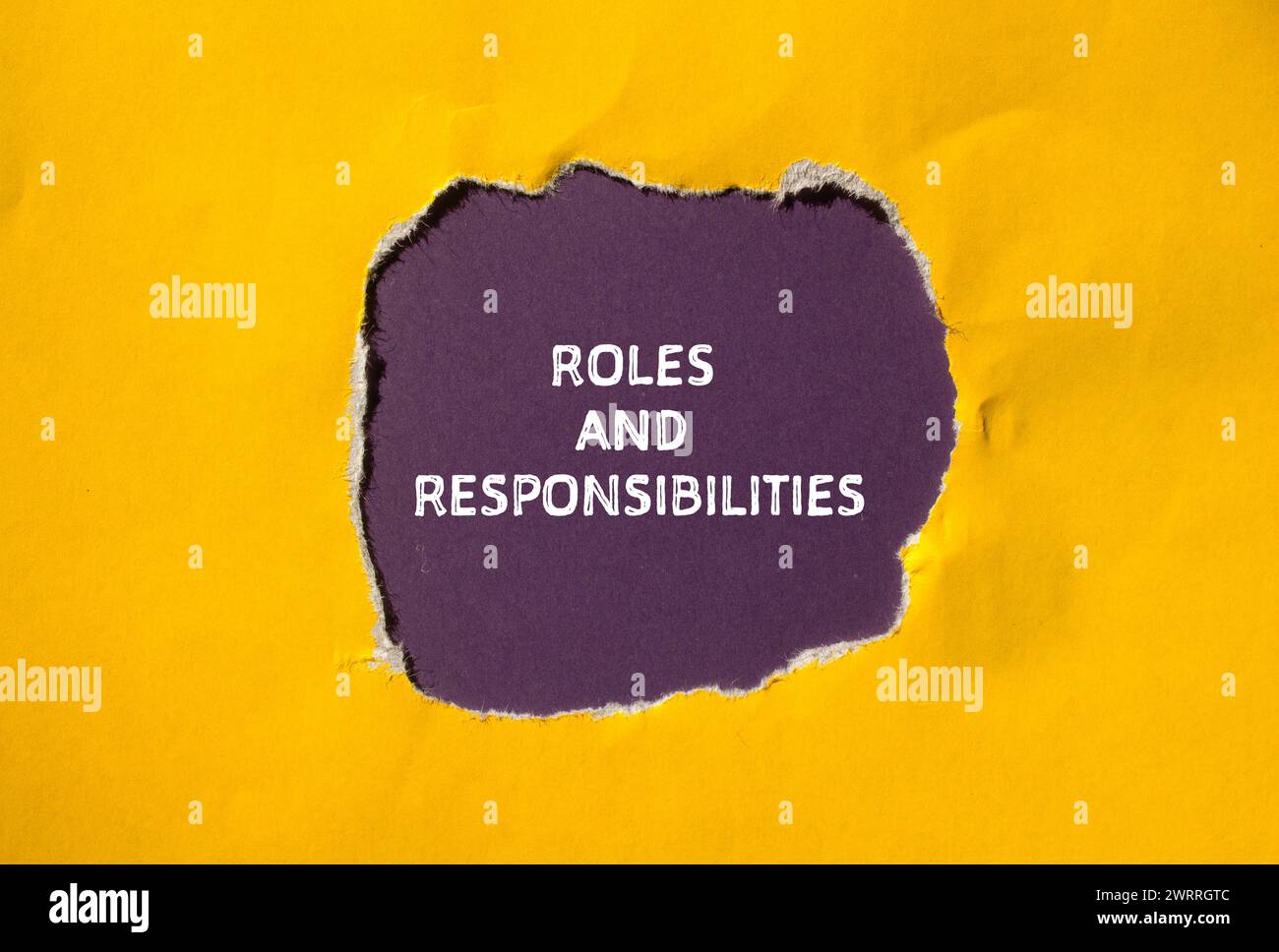 Wörter für Rollen und Verantwortlichkeiten auf gelbem Papier mit violettem Hintergrund. Konzeptsymbol. Kopierbereich. Stockfoto