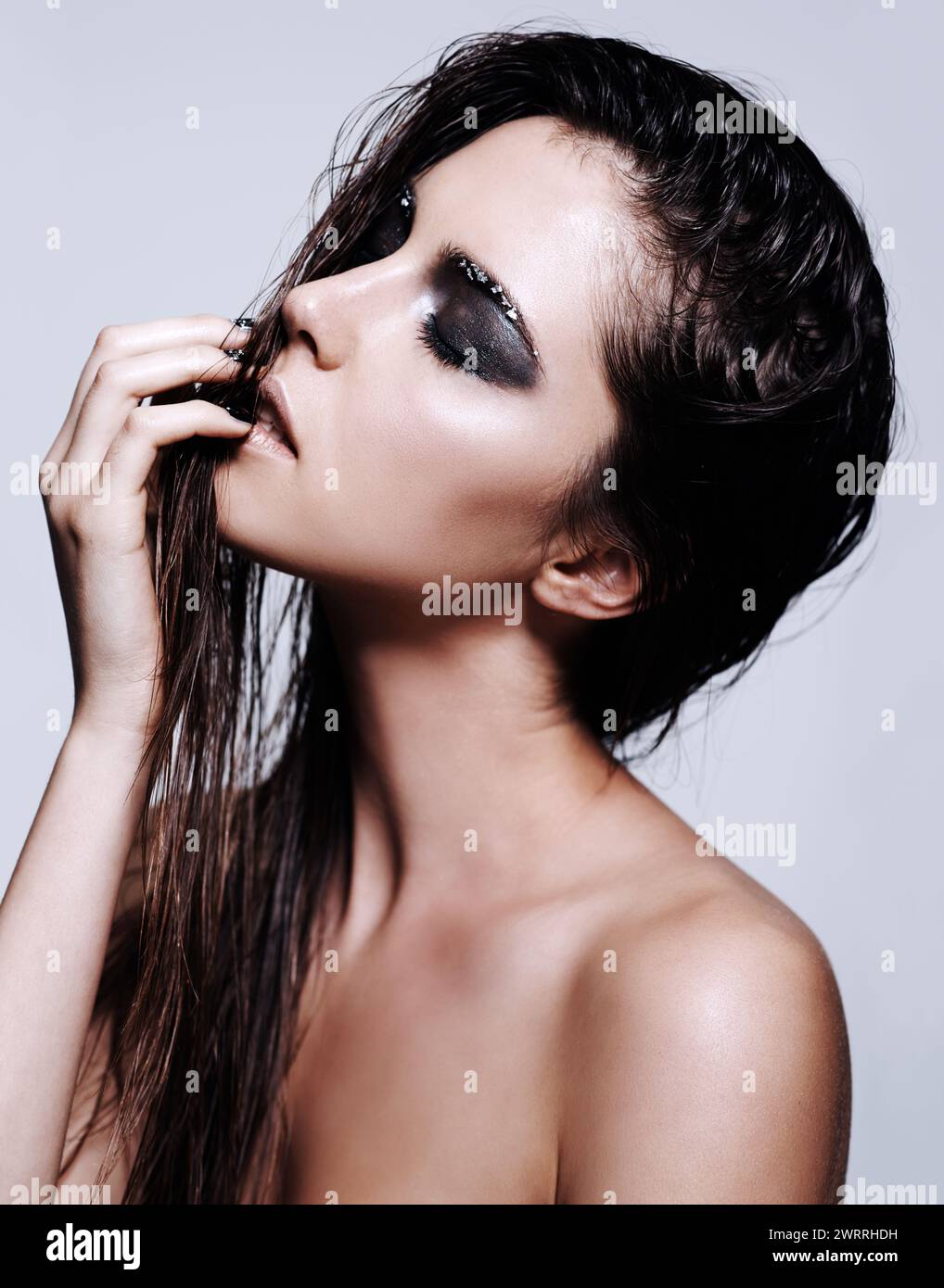 Frau, Schönheit und Make-up mit Lidschatten oder Mode in Hautpflege auf grauem Studiohintergrund. Gesicht einer Frau, Brünette oder Model in der Haarpflege mit Stockfoto