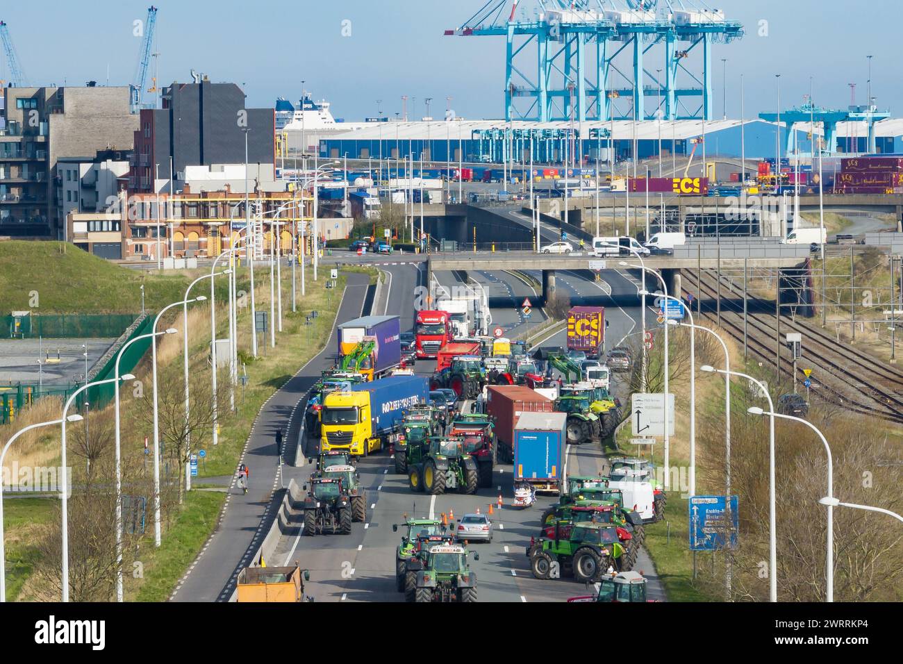 Zeebrugge, Belgien. März 2024. Die Luftaufnahme zeigt Lkw und Traktoren, die während eines Bauernprotests am Donnerstag, den 14. März 2024, den Zugang von LKWs zum Hafen Antwerpen-Brügge in Zeebrugge blockierten. Zwei unabhängige Junglandwirtenverbände protestieren weiterhin gegen die strengen Stickstoffvorschriften für Landwirte. Durch die Sperrung der Häfen wollen die Landwirte darauf hinweisen, dass es vor allem die Industrie ist, die Stickstoff ausstößt, und nicht die Landwirtschaft. BELGA FOTO KURT DESPLENTER Credit: Belga Nachrichtenagentur/Alamy Live News Stockfoto