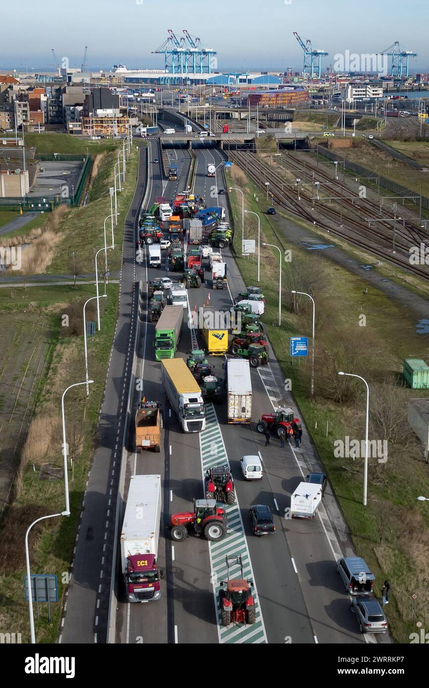 Zeebrugge, Belgien. März 2024. Die Luftaufnahme zeigt Lkw und Traktoren, die während eines Bauernprotests am Donnerstag, den 14. März 2024, den Zugang von LKWs zum Hafen Antwerpen-Brügge in Zeebrugge blockierten. Zwei unabhängige Junglandwirtenverbände protestieren weiterhin gegen die strengen Stickstoffvorschriften für Landwirte. Durch die Sperrung der Häfen wollen die Landwirte darauf hinweisen, dass es vor allem die Industrie ist, die Stickstoff ausstößt, und nicht die Landwirtschaft. BELGA FOTO KURT DESPLENTER Credit: Belga Nachrichtenagentur/Alamy Live News Stockfoto