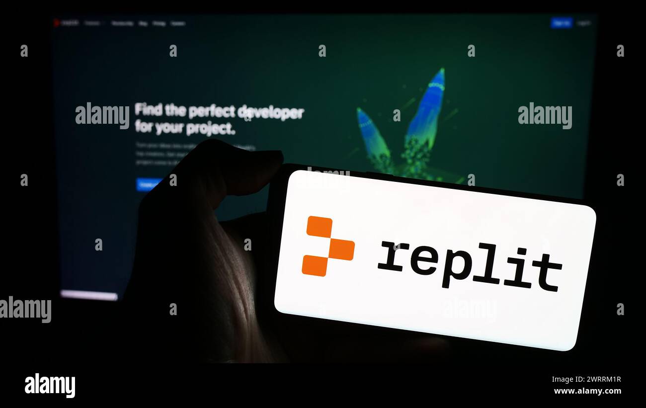 Person, die ein Mobiltelefon mit dem Logo des amerikanischen Softwareentwicklungsplattform-Unternehmens Replit Inc. Vor der Webseite hält. Schwerpunkt auf dem Display des Telefons. Stockfoto