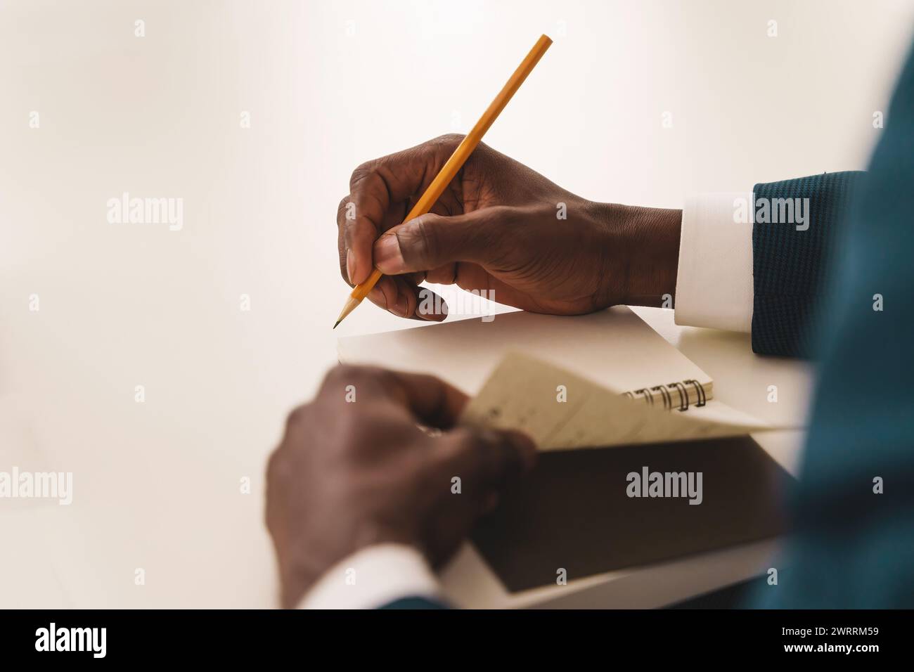 Nahaufnahme der Notizen: Die Hände eines Geschäftsmanns, die während eines Firmensitzes in einen Notizblock schreiben – Fokus auf effektives Notizen. Stockfoto