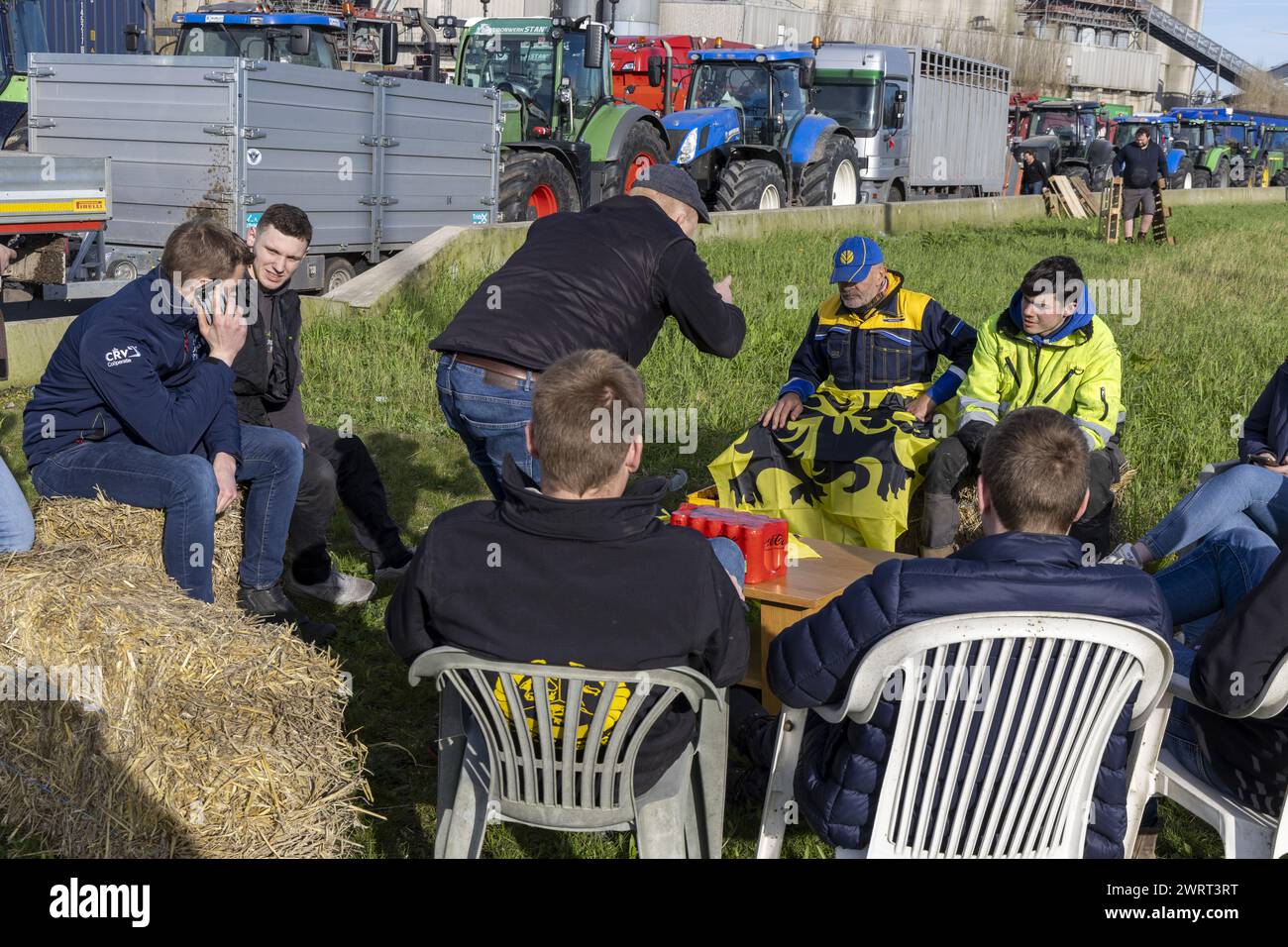 Gent, Belgien. März 2024. Die Bauern haben sich mit Gartenstühlen, Strohballen und einem Tisch bei einem Bauernprotest, der am Donnerstag, den 14. März 2024 die Einfahrt von LKWs zum Hafen von Gent blockierte, bequem gemacht. Zwei unabhängige Junglandwirte-Verbände protestieren weiterhin gegen die strengen Stickstoffvorschriften für Landwirte. Durch die Sperrung der Häfen wollen die Landwirte darauf hinweisen, dass es vor allem die Industrie ist, die Stickstoff ausstößt, und nicht die Landwirtschaft. BELGA FOTO NICOLAS MAETERLINCK Credit: Belga News Agency/Alamy Live News Stockfoto