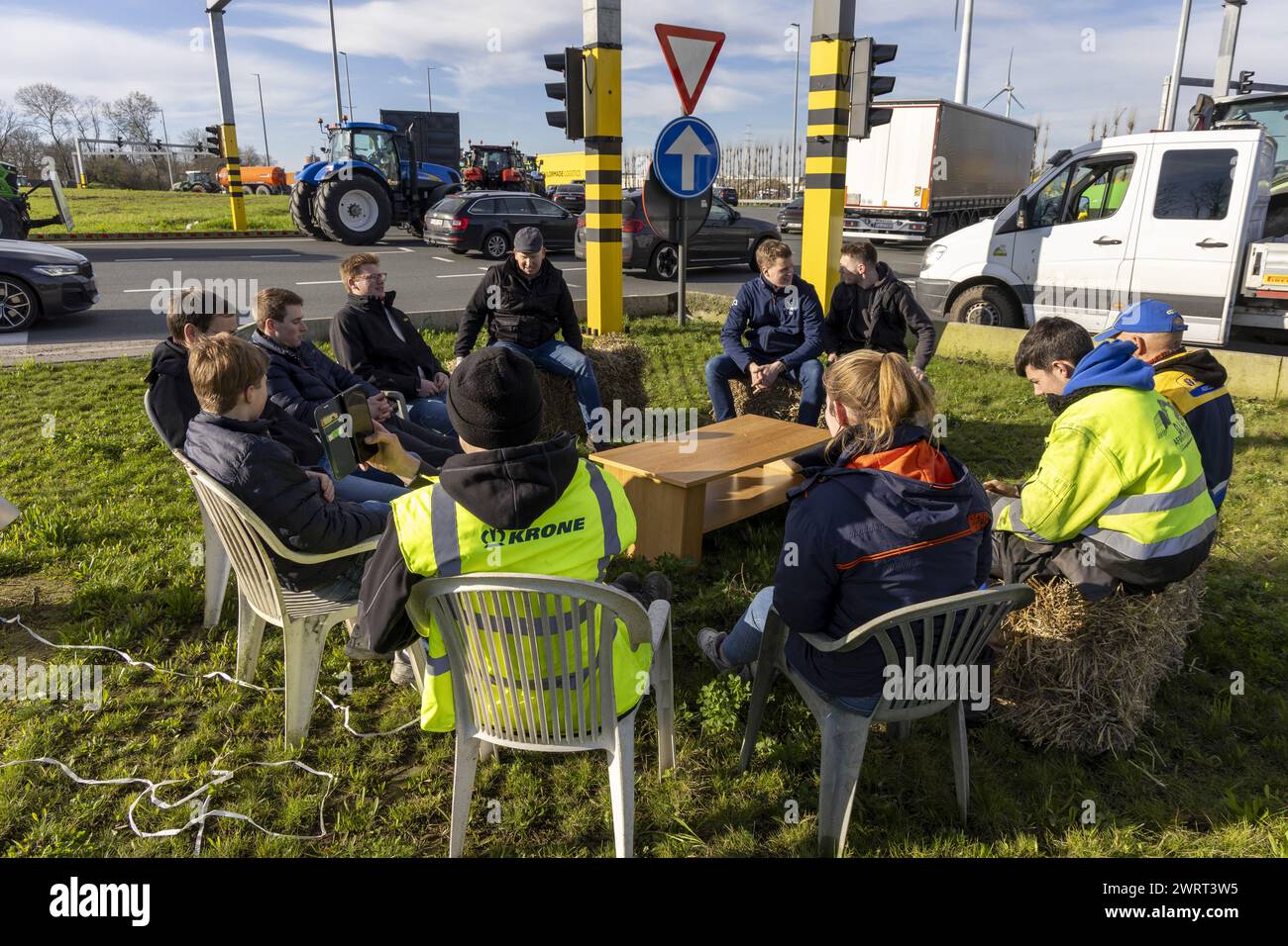 Gent, Belgien. März 2024. Die Bauern haben sich mit Gartenstühlen, Strohballen und einem Tisch bei einem Bauernprotest, der am Donnerstag, den 14. März 2024 die Einfahrt von LKWs zum Hafen von Gent blockierte, bequem gemacht. Zwei unabhängige Junglandwirte-Verbände protestieren weiterhin gegen die strengen Stickstoffvorschriften für Landwirte. Durch die Sperrung der Häfen wollen die Landwirte darauf hinweisen, dass es vor allem die Industrie ist, die Stickstoff ausstößt, und nicht die Landwirtschaft. BELGA FOTO NICOLAS MAETERLINCK Credit: Belga News Agency/Alamy Live News Stockfoto