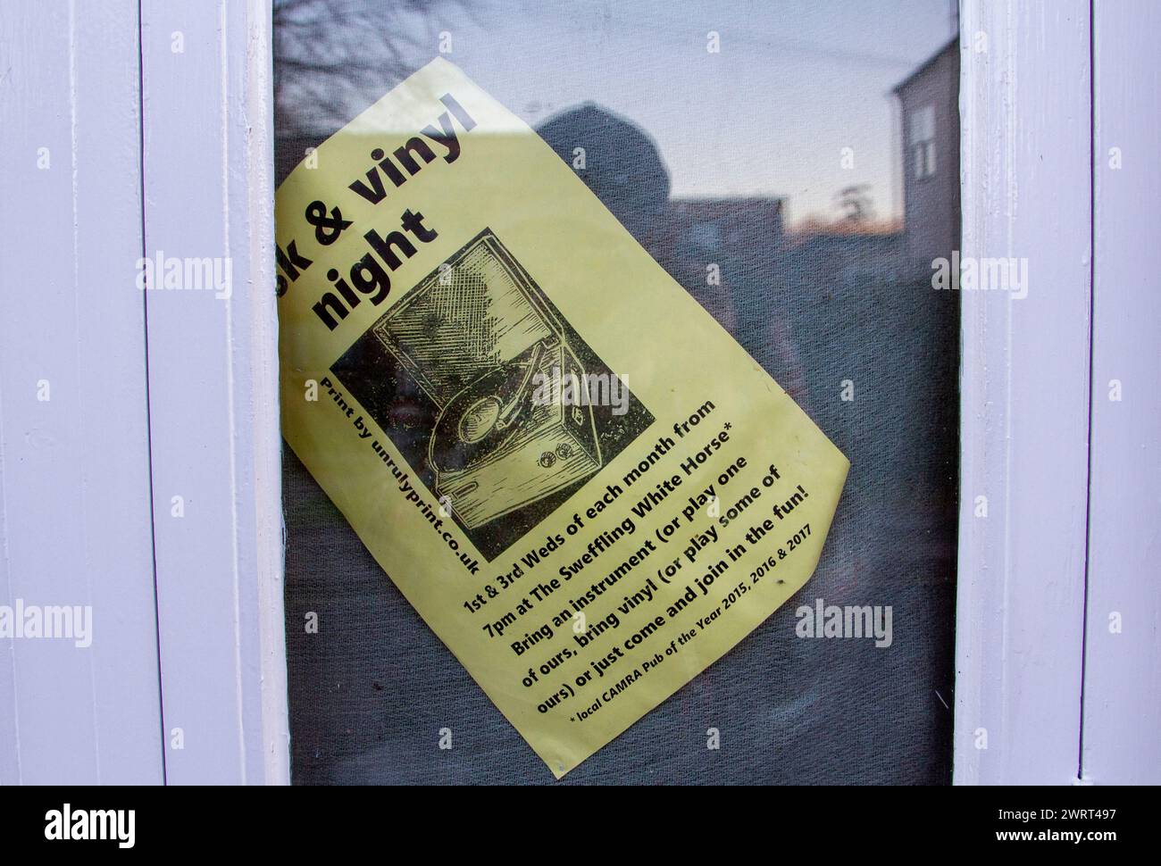 Gedruckter Flyer auf gelbem Papier in einem Fenster und unbeholfen lehnen sich, um eine Vinyl-Musik-Nacht im Pub The Sweffling White Horse in Suffolk anzukündigen Stockfoto