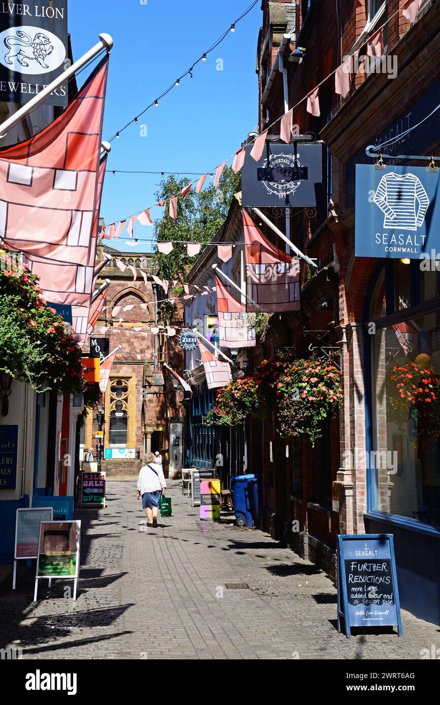 Menschen gehen entlang der Gandy Street, gesäumt von Geschäften und Restaurants, mit einem Teil des Royal Albert Memorial Museums und der Kunstgalerie auf der Rückseite, Exeter. Stockfoto