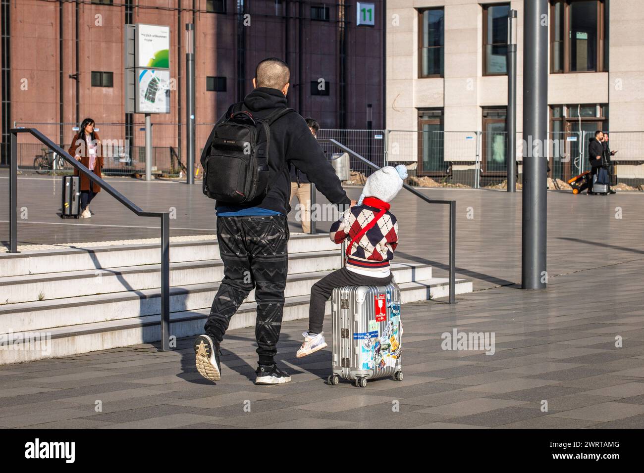 Mann, der ein Kind auf einem Trolley fährt, MesseCity im Kölner Deutz. Mann faehrt ein Kind auf einem Trolley, MesseCity im Stadtteil Stockfoto