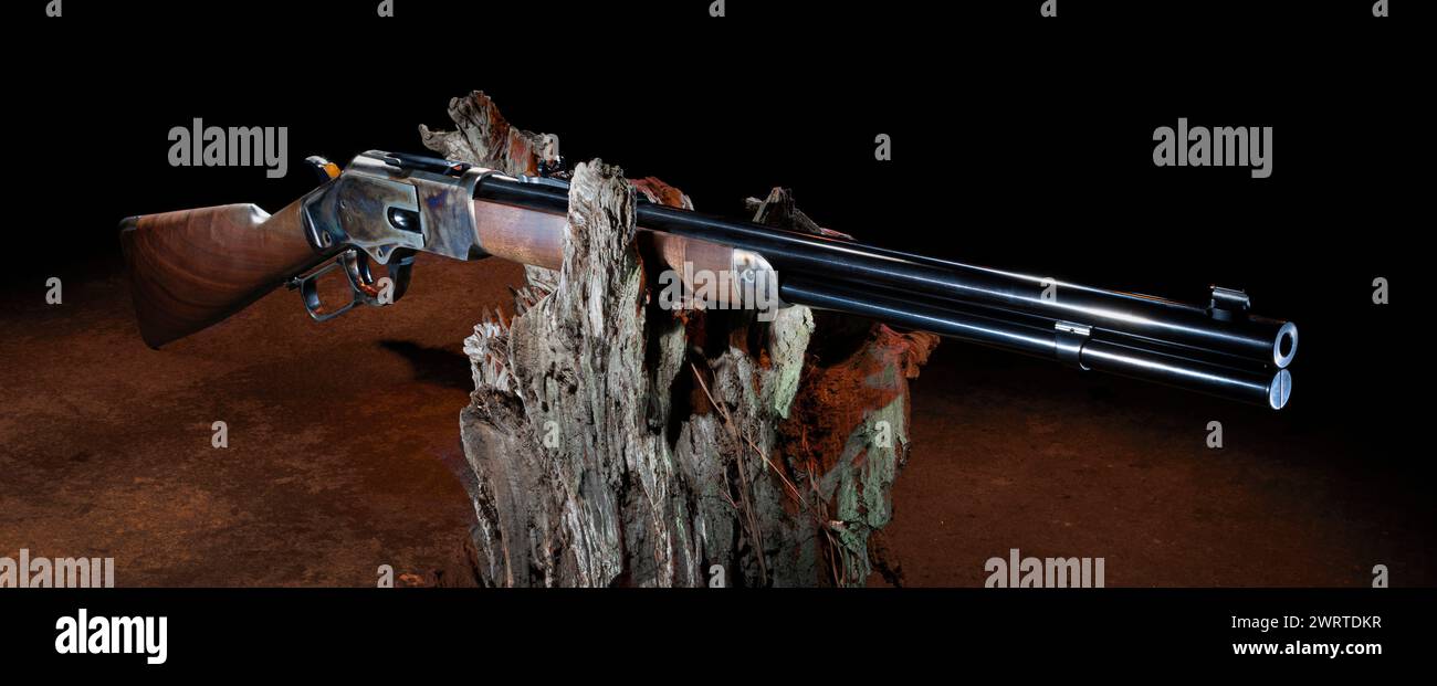 Orangefarbene Hinterleuchtung auf einem alten Westernschieber mit einem Holzstock und gebläutem Metall auf einem toten Stamm. Stockfoto
