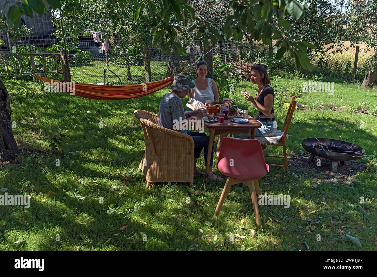 Familie frühstückt im Garten unter einem Kirschbaum, Mecklenburg-Vorpommern, Deutschland Stockfoto