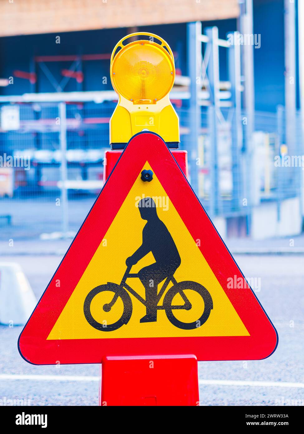 Am Straßenrand befindet sich ein gelbes und rotes Warnschild. Das Zeichen ist wahrscheinlich vorhanden, um Radfahrer vor potenziellen Gefahren zu warnen. Stockfoto