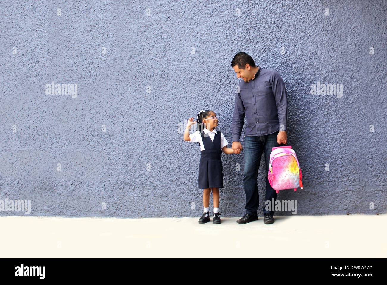 Der geschiedene alleinerziehende Vater holt seine brünette Latina-Tochter von der Schule ab, trägt ihren Rucksack und erzählt von seinem Tag Stockfoto