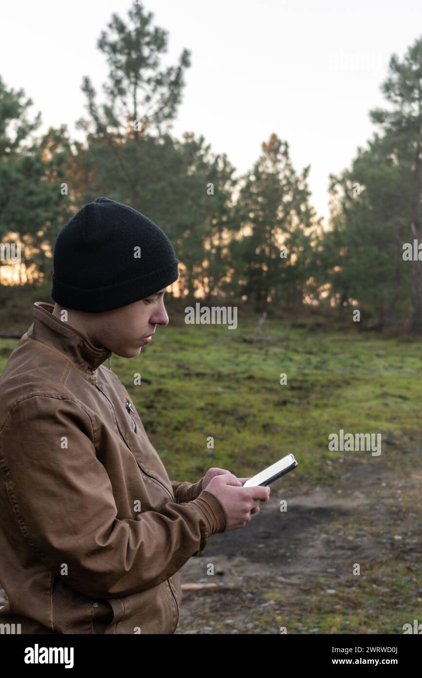 Stock-Foto eines Kaukasiers in der Natur, der auf sein Handy schaut Stockfoto