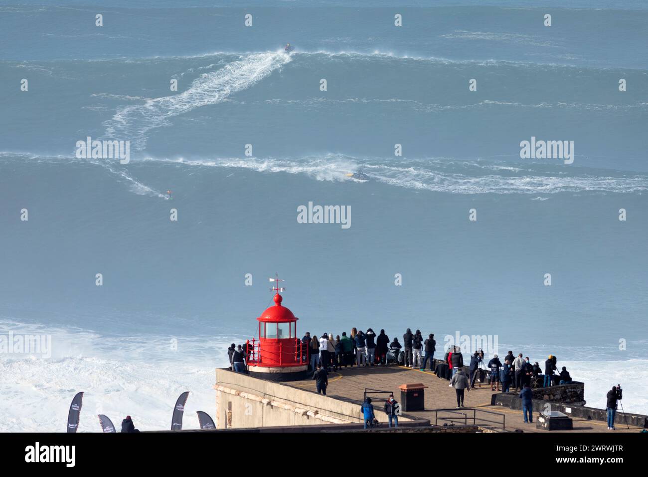 Portugal, Region Oeste, Nazaré, Surfer und Support Jet Skis fahren während des Free Surfing Events 2022 in der Nähe von Praia do Norte auf riesigen Wellen Stockfoto
