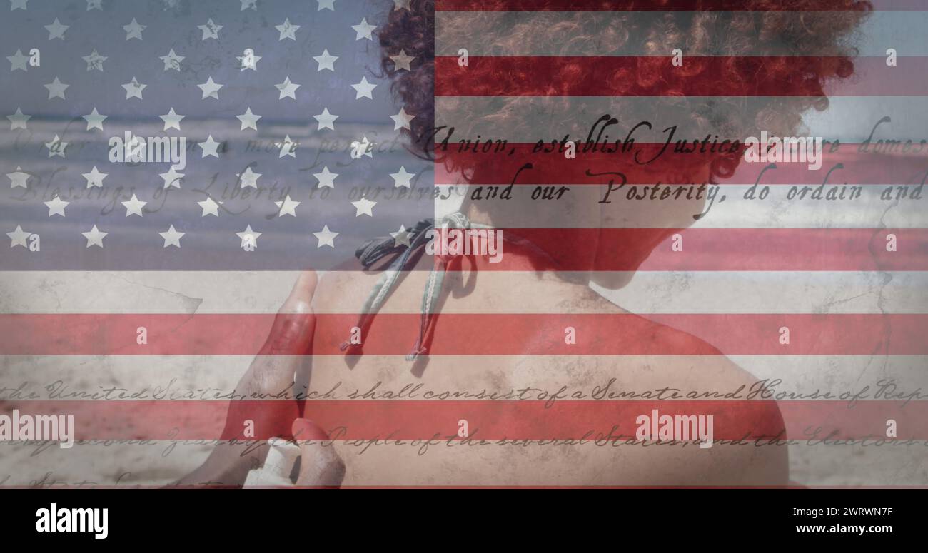 Bild einer amerikanischen Flagge, die in den Sommerferien einen Verfassungstext über rassistische Frauen am Meer schwenkt, sie Stockfoto