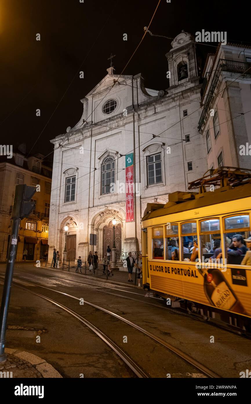 Lissabon, Portugal - 15. Oktober 2023: Kirche der Heiligen Maria Magdalena (Portugiesisch: Igreja da Madalena) und berühmte Straßenbahn Nr. 28 bei Nacht. Stockfoto