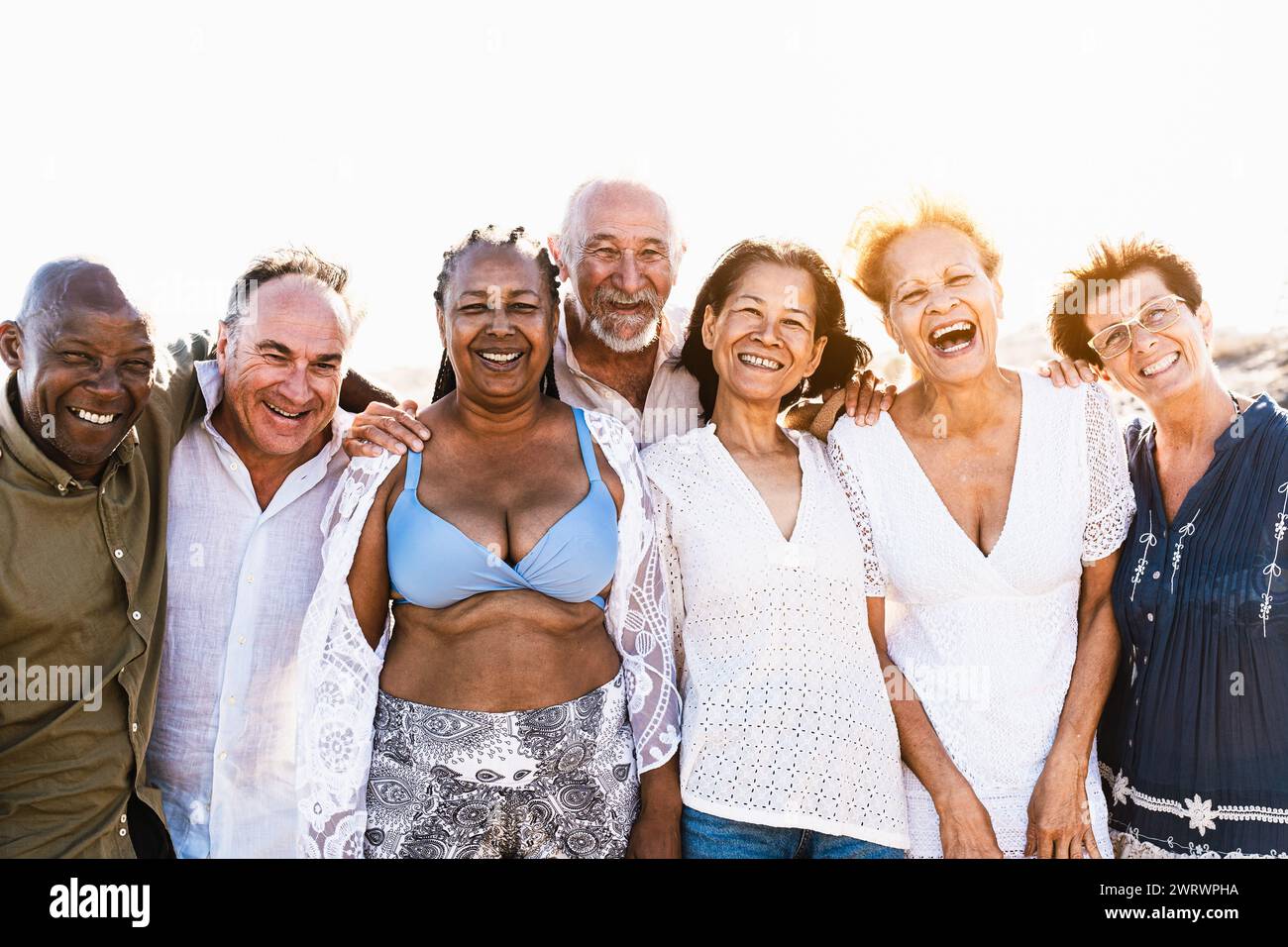 Glückliche, multirassische Seniorenfreunde, die Spaß haben, am Strand in die Kamera zu lächeln - verschiedene ältere Menschen genießen Sommerferien Stockfoto