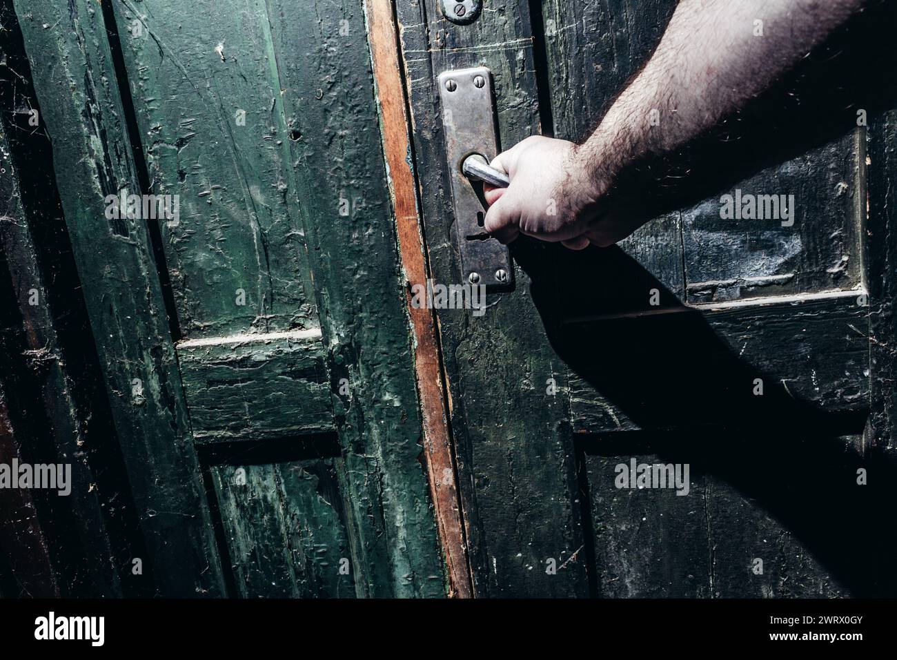 Foto von männlicher Hand, die alte, veraltete staubige Tür öffnet. Horror-Konzept. Stockfoto