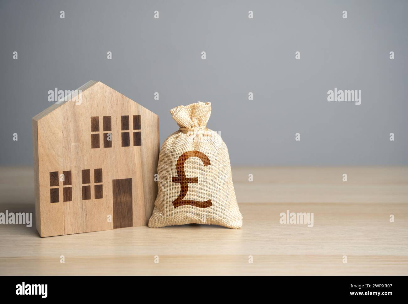 Eine hölzerne Hausfigur und ein britisches Pfund Sterling Geldbeutel. Steuern. Bewertung des Eigenschaftswerts. Machen Sie einen Deal. Wohnimmobilienpreise. Kauf und Verkauf von Immobilien Stockfoto