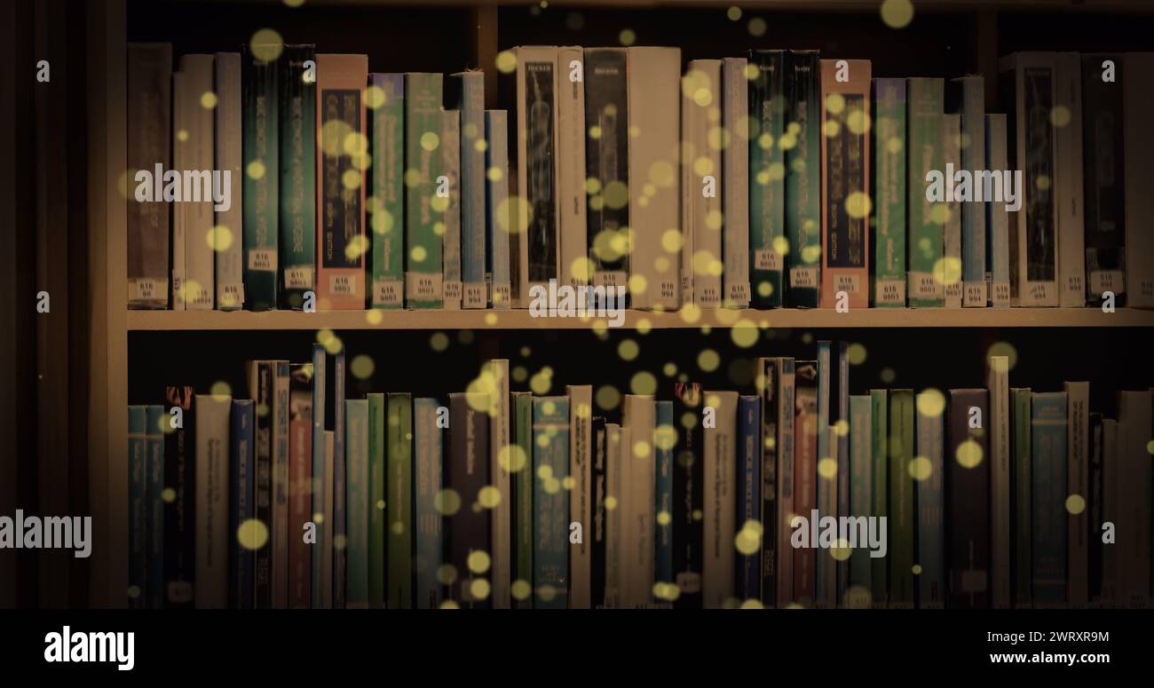 Bild von leuchtenden Flecken über Büchern im Regal Stockfoto
