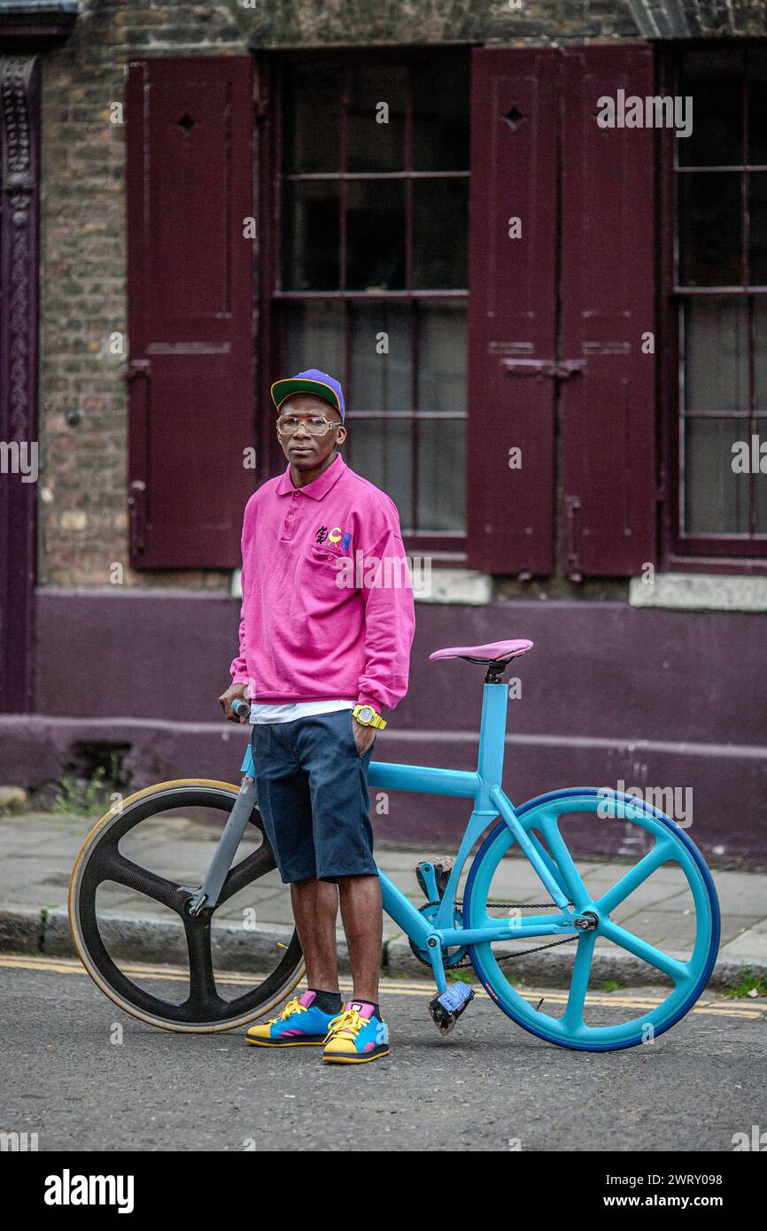 Junger Hipster, der mit festem Fahrrad auf der Straße in Bricklane East London, Großbritannien, steht Stockfoto