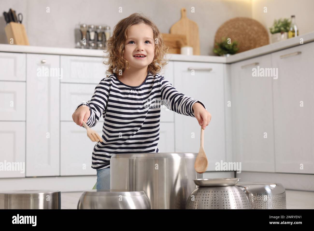 Kleines Mädchen, das vorgibt, Trommeln auf Töpfen in der Küche zu spielen Stockfoto