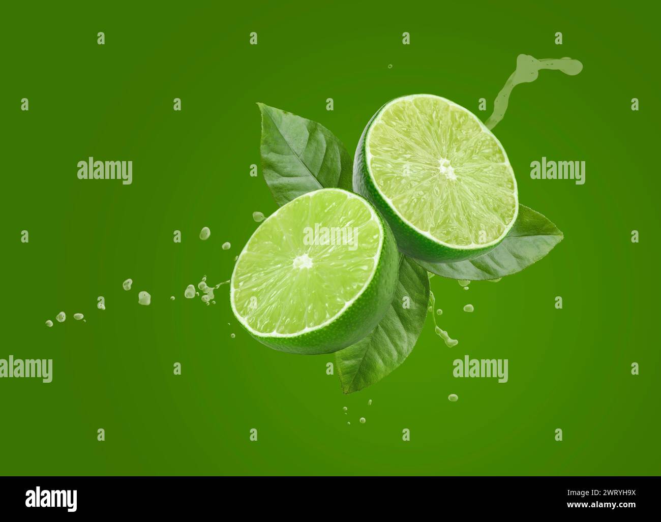 Limette, Blätter und spritzender Saft auf grünem Hintergrund Stockfoto