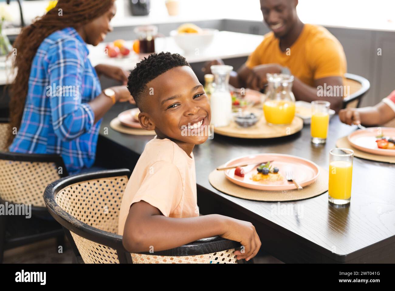 Ein junger afroamerikanischer Junge lächelt während eines Familienfrühstücks zu Hause Stockfoto