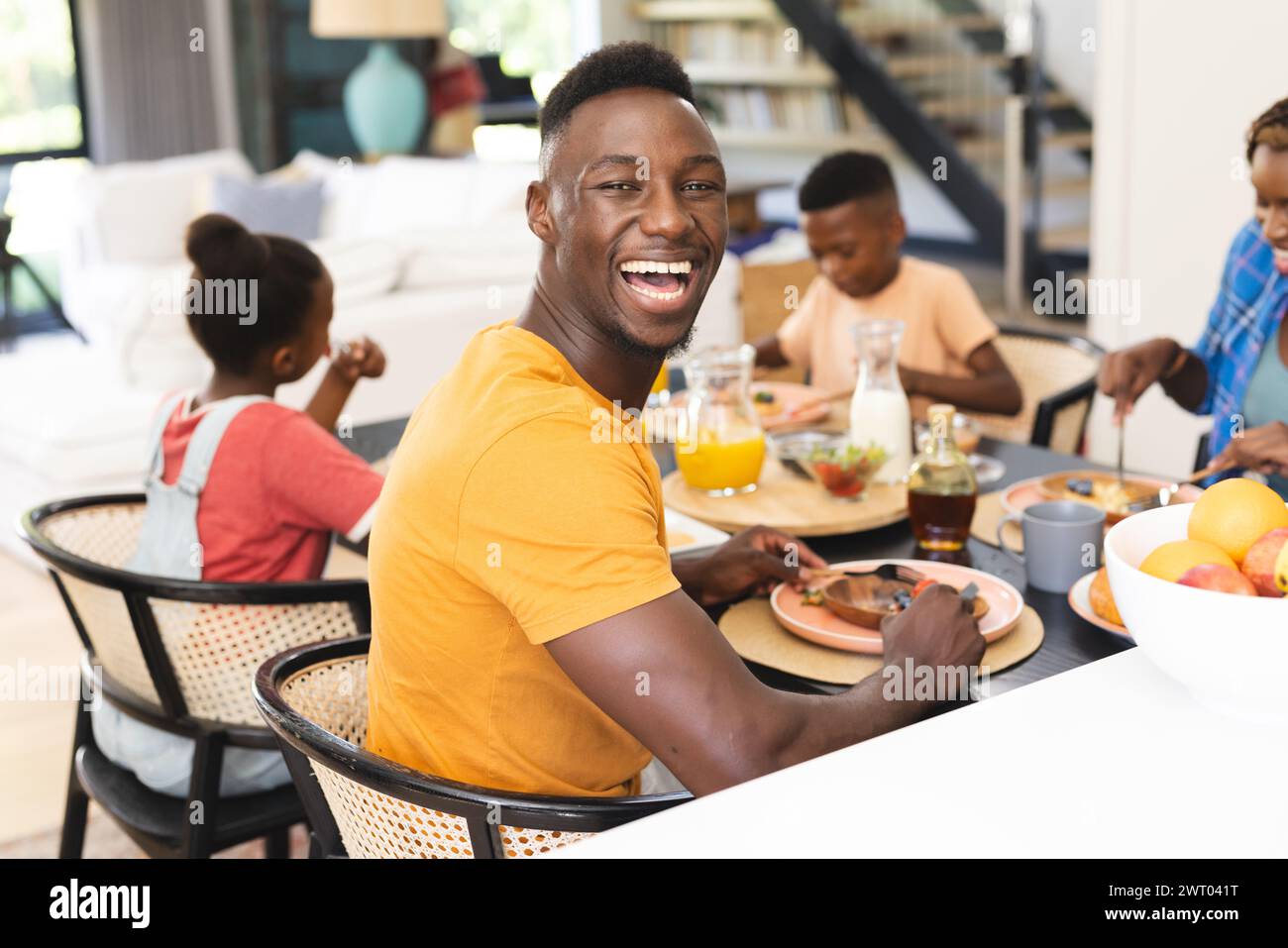 Beim Frühstück in der Küche zu Hause genießt ein afroamerikanischer Vater eine Mahlzeit mit seiner Familie Stockfoto