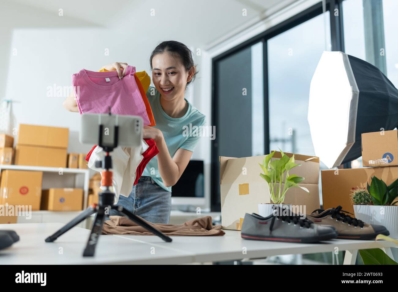 Schöne junge Frau, die in einem Online-Shop arbeitet und legere Kleidung trägt, überprüft die Laptop-Adresse des Kunden und die Produktinformationen Sie besitzt eine kleine Stockfoto