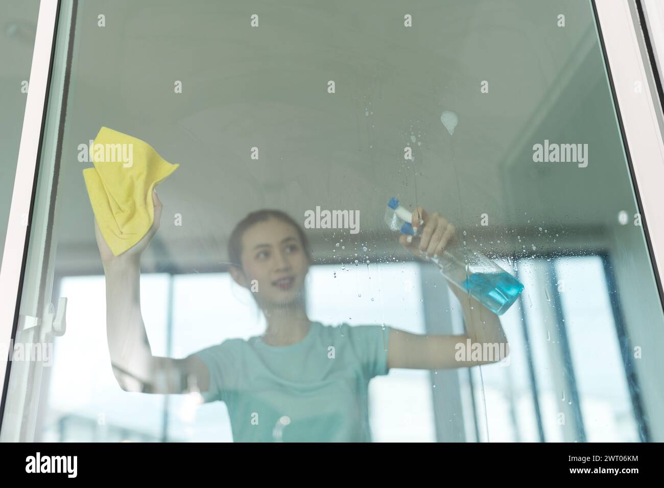Schöne Frau, die den Hausspiegel putzt. Stockfoto