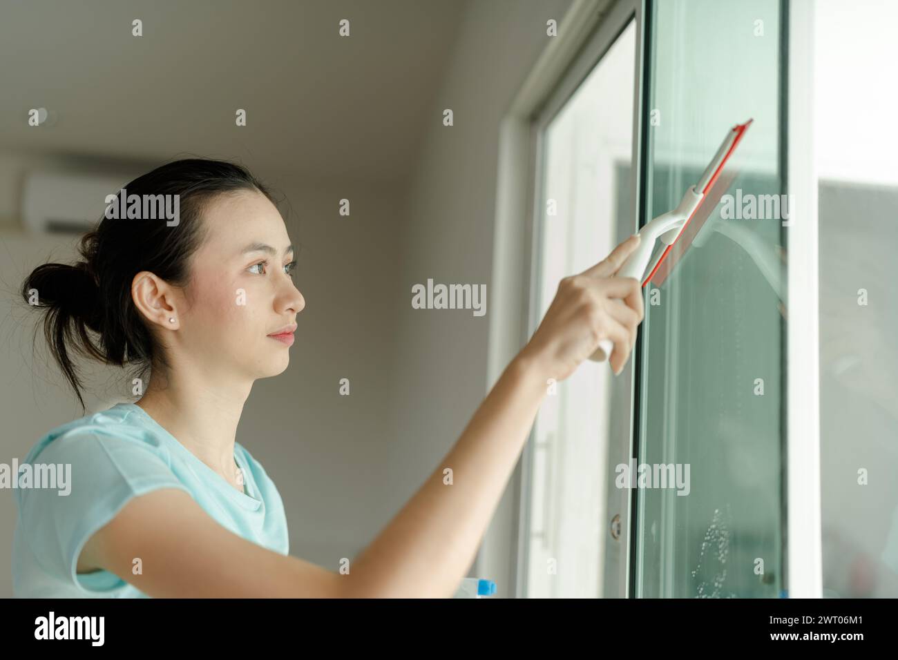 Schöne Frau, die den Hausspiegel putzt. Stockfoto