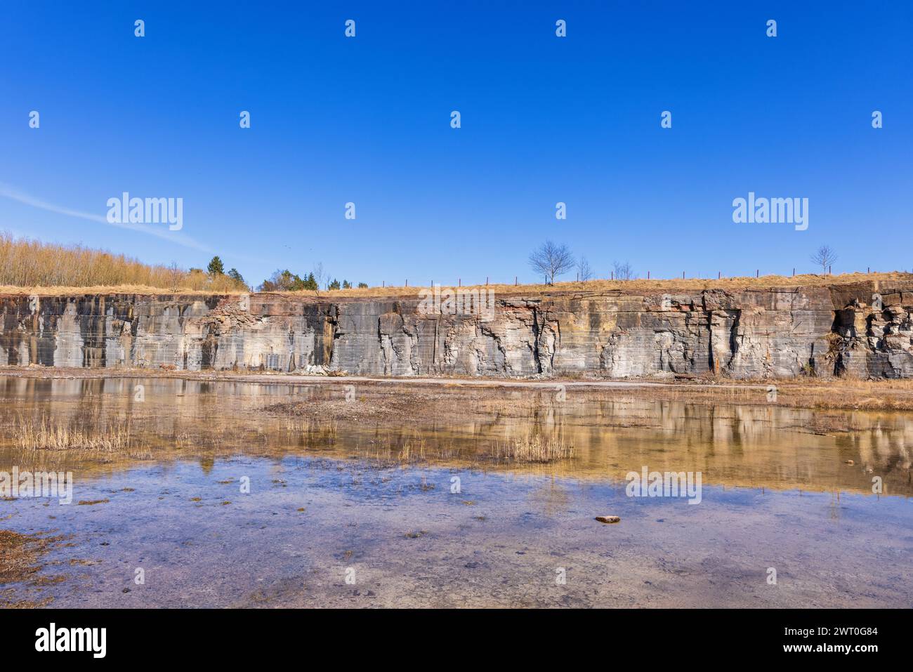 Felswände an einem alten stillgelegten Kalksteinbruch mit Wasserreflektionen an einem sonnigen Frühlingstag Stockfoto