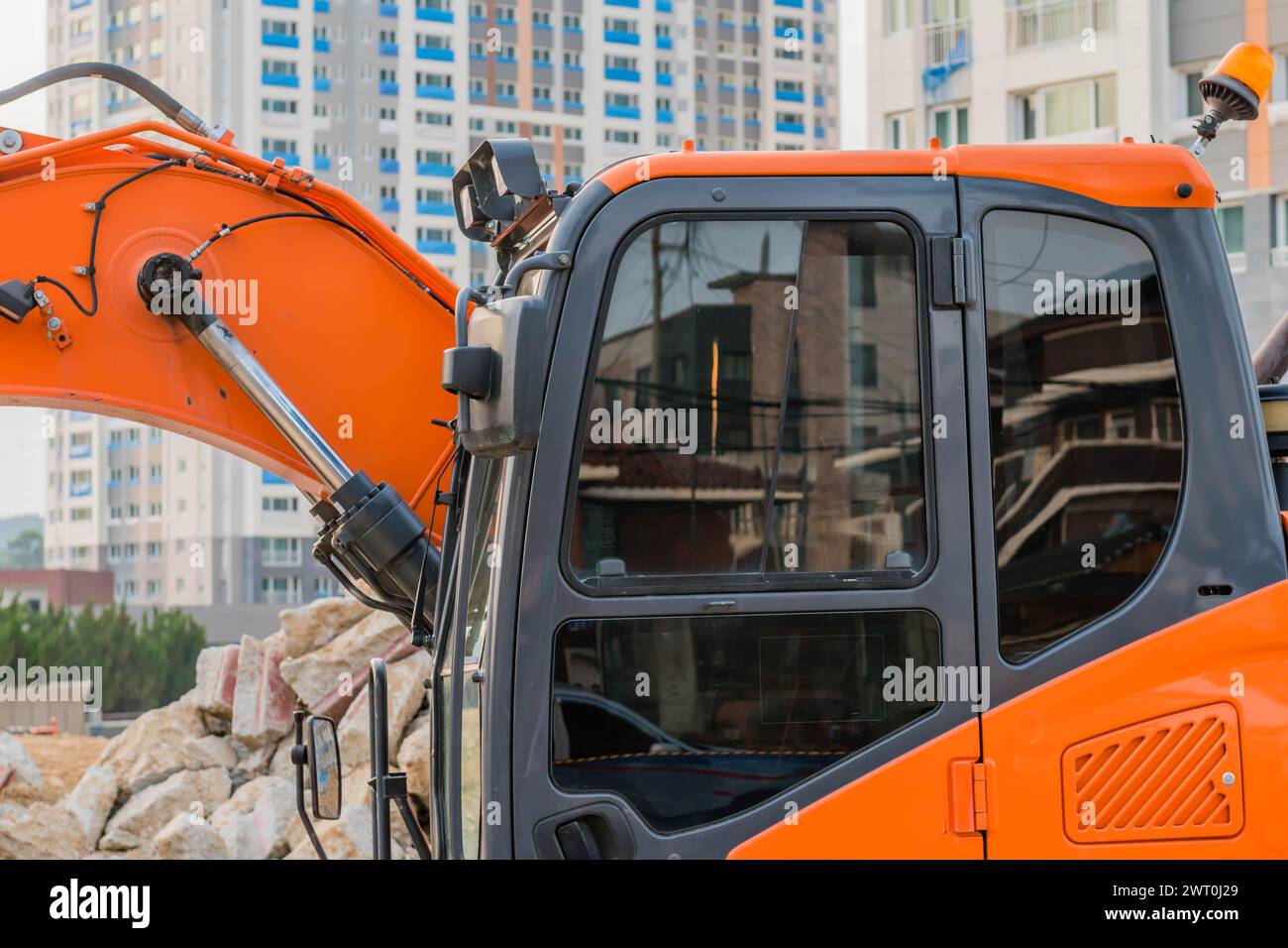 Kabine mit orangefarbenem Baggerlader auf der Baustelle mit Hochhaus im Hintergrund in Daejeon, Südkorea Stockfoto