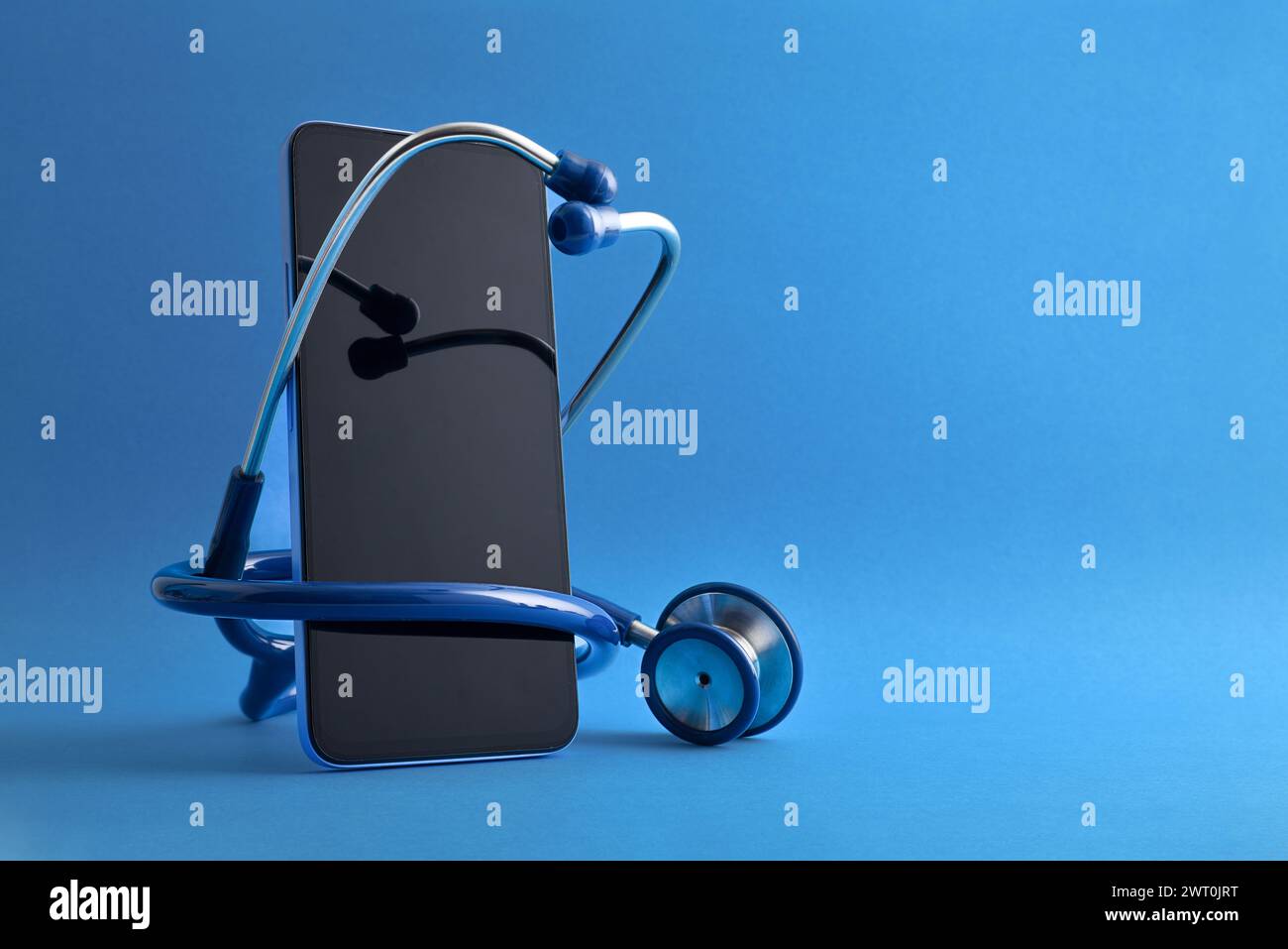 Internet-Gesundheitsdienst mit Stethoskop um ein Mobiltelefon auf blauem isoliertem Hintergrund. Vorderansicht. Stockfoto